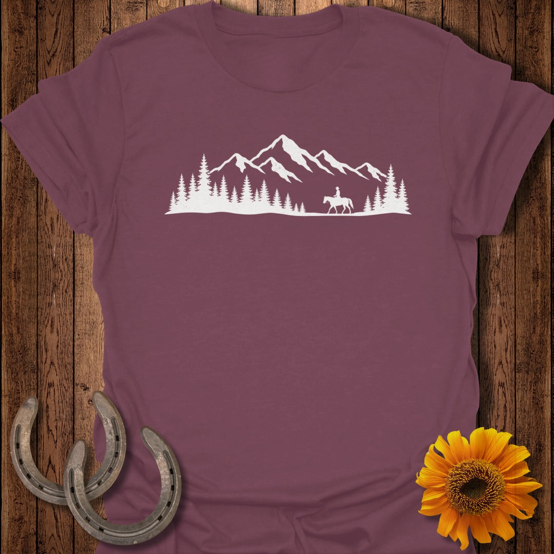 White silhouette of a rider on a horse against a mountain and pine tree landscape.