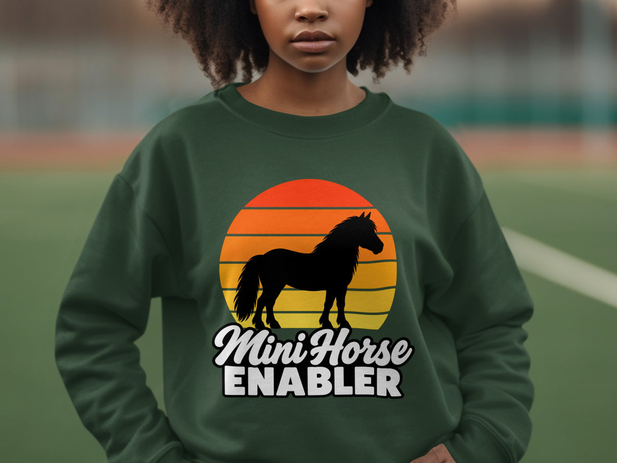 A person wearing a dark green sweatshirt featuring a graphic of a horse and sunset.