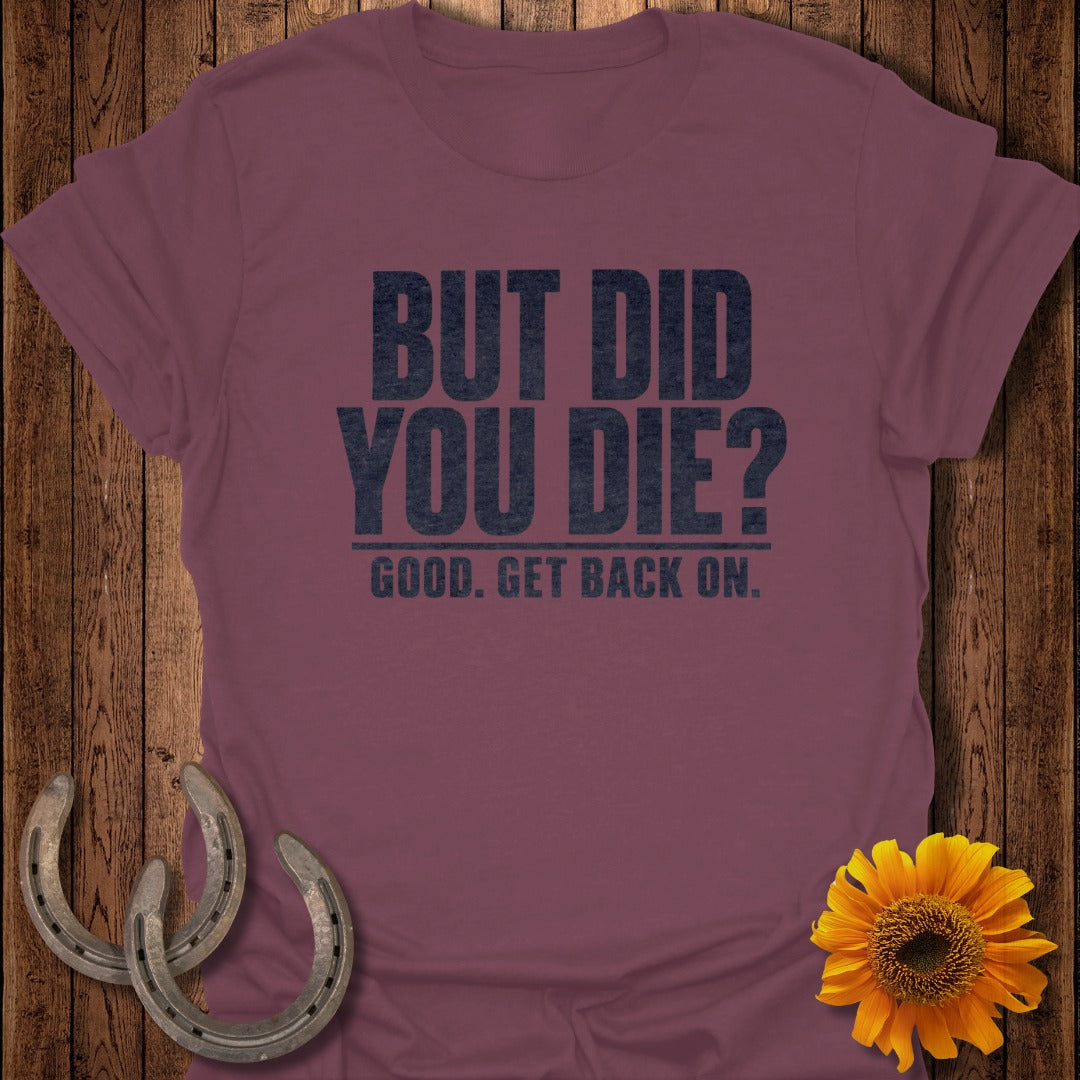 Maroon t-shirt with black text reading "BUT DID YOU DIE? GOOD. GET BACK ON." and rustic decor.