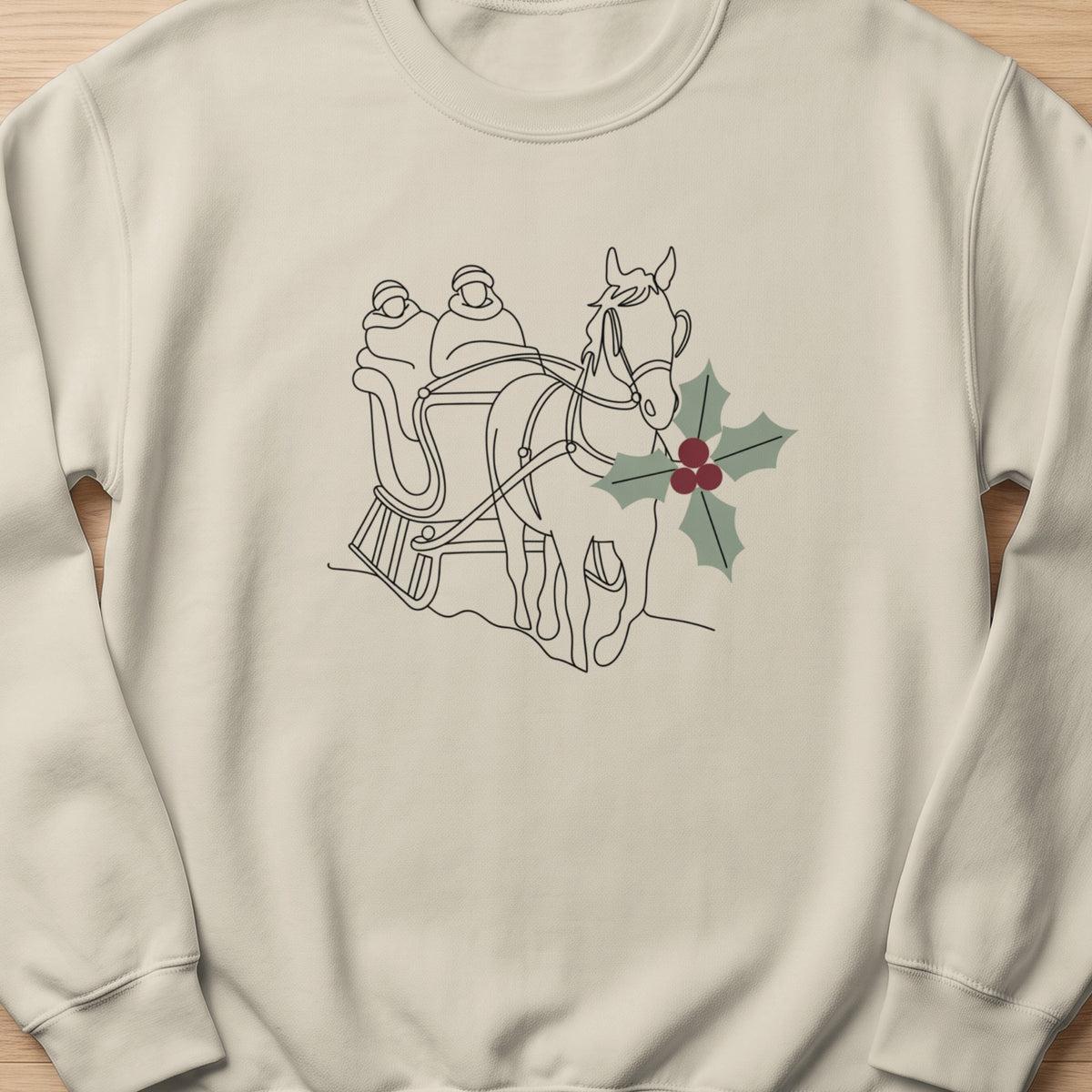 Line art of horse and sleigh with passengers and holly sprig on a cream sweatshirt.