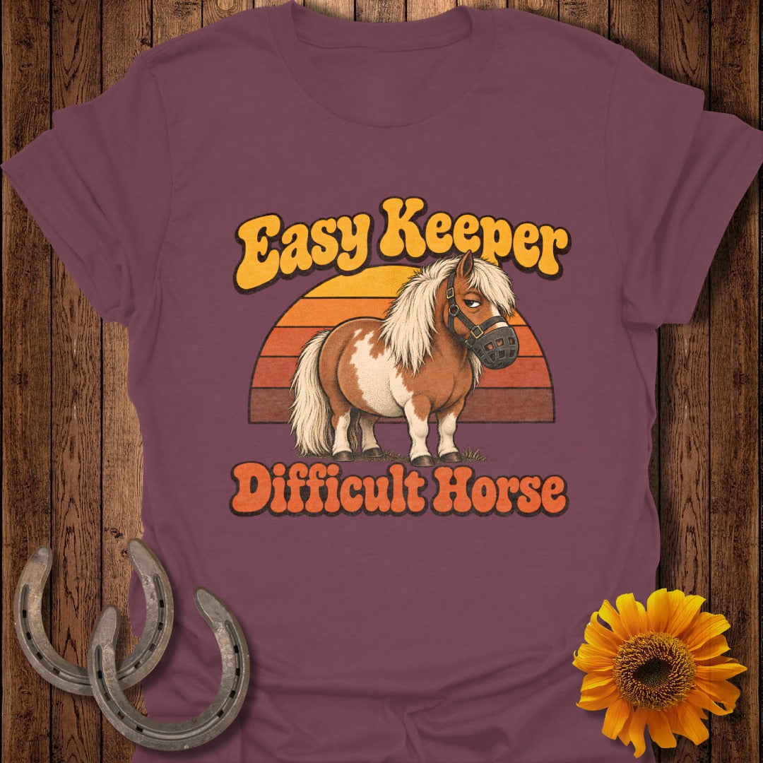 Brown and white pony wearing a muzzle with text "Easy Keeper Difficult Horse".