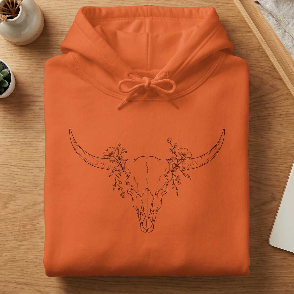 Orange hoodie with a black outline drawing of a bull skull and flowers.