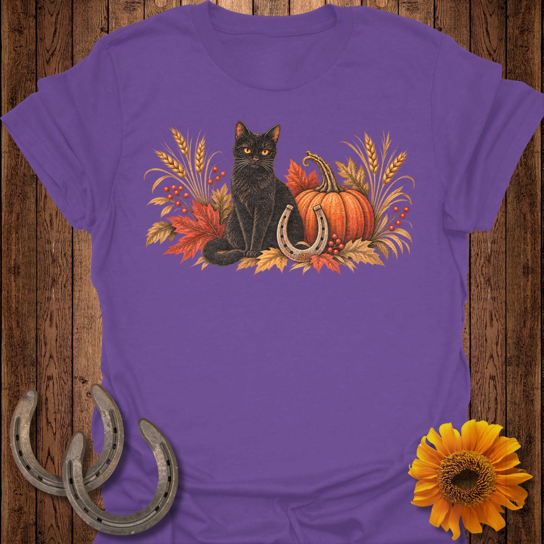 Black cat with pumpkin, horseshoe, and autumn leaves graphic on purple t-shirt.
