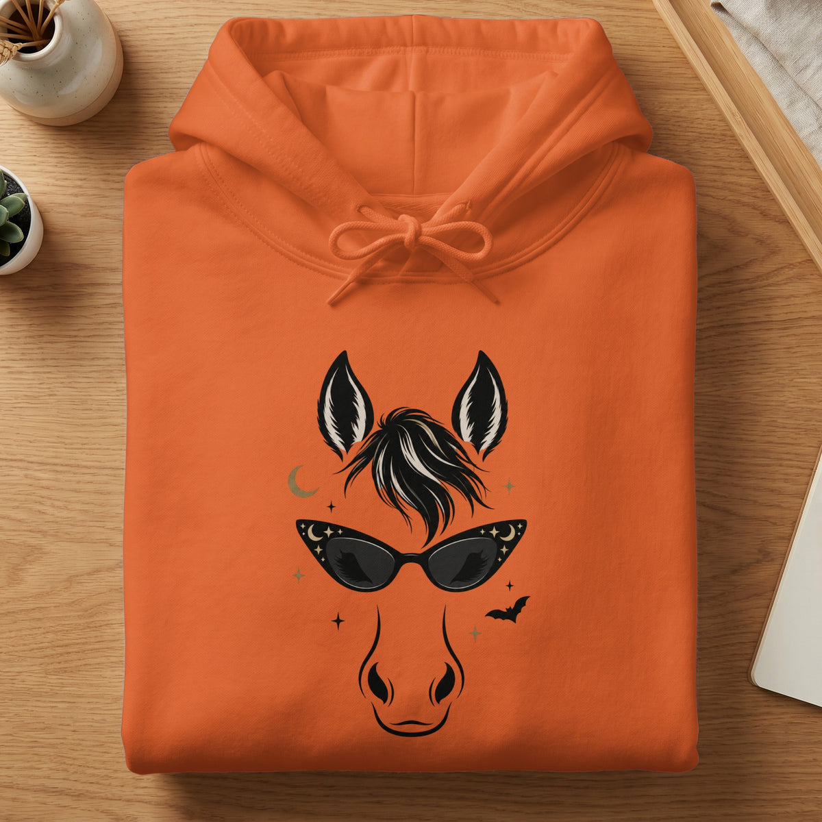 Orange hoodie with a graphic of a horse face wearing sunglasses and Halloween elements.