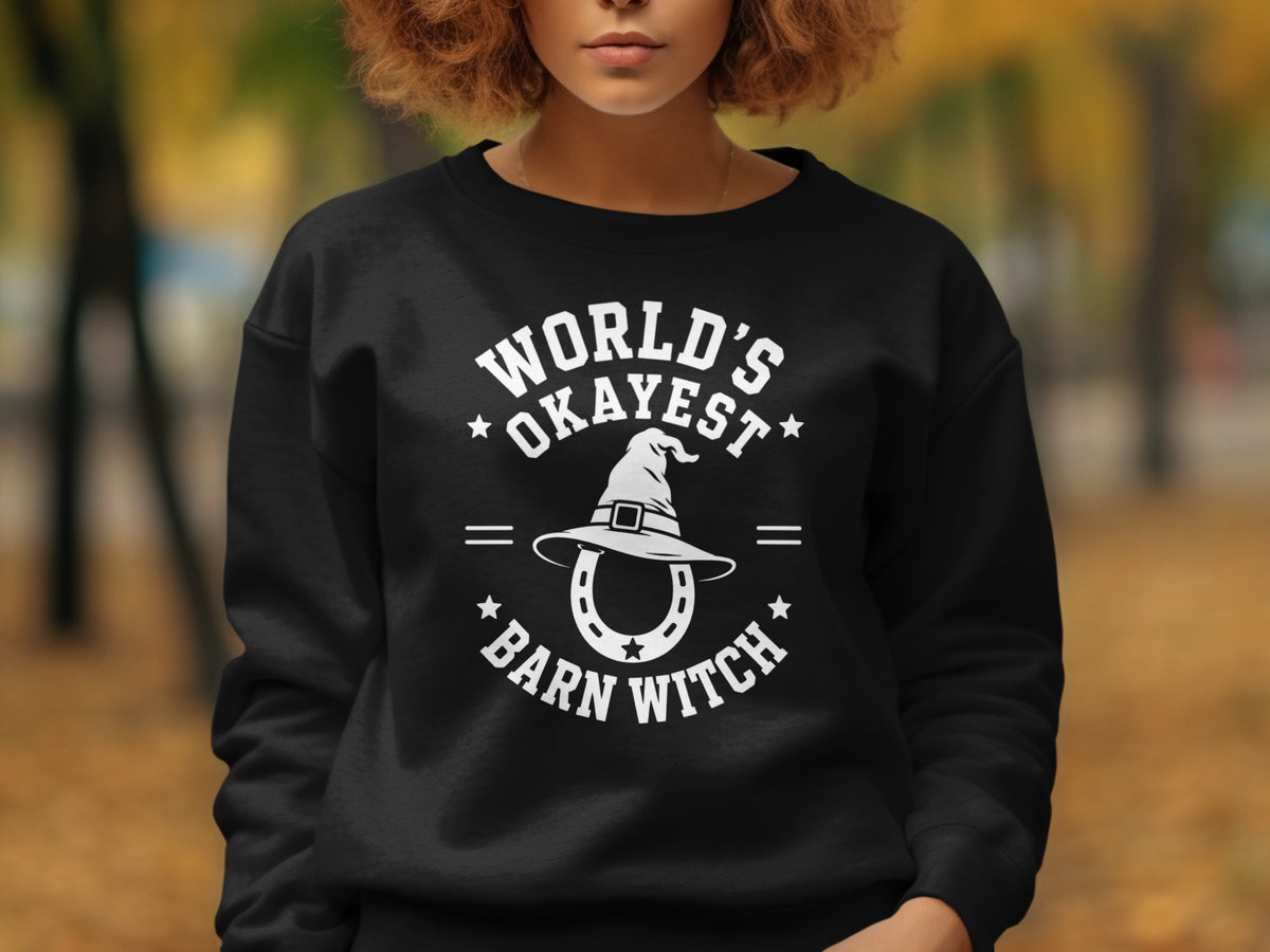 Black sweatshirt with white text and graphics reading "World's Okayest Barn Witch".