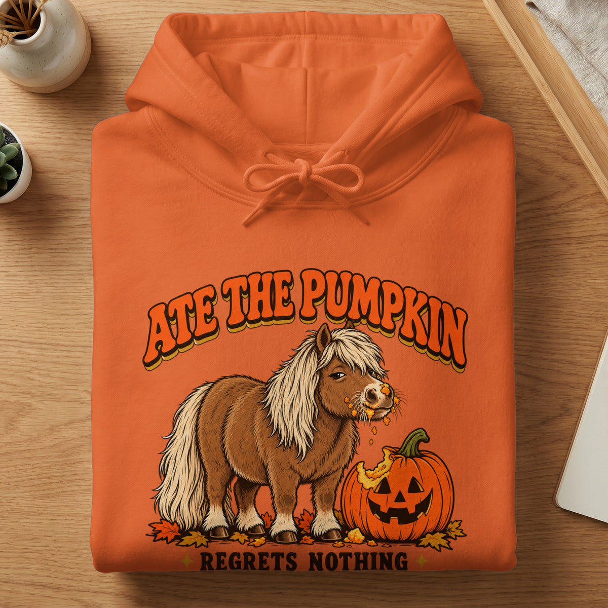 Orange hoodie with graphic of pony eating pumpkin, "Ate the Pumpkin" and "Regrets Nothing".