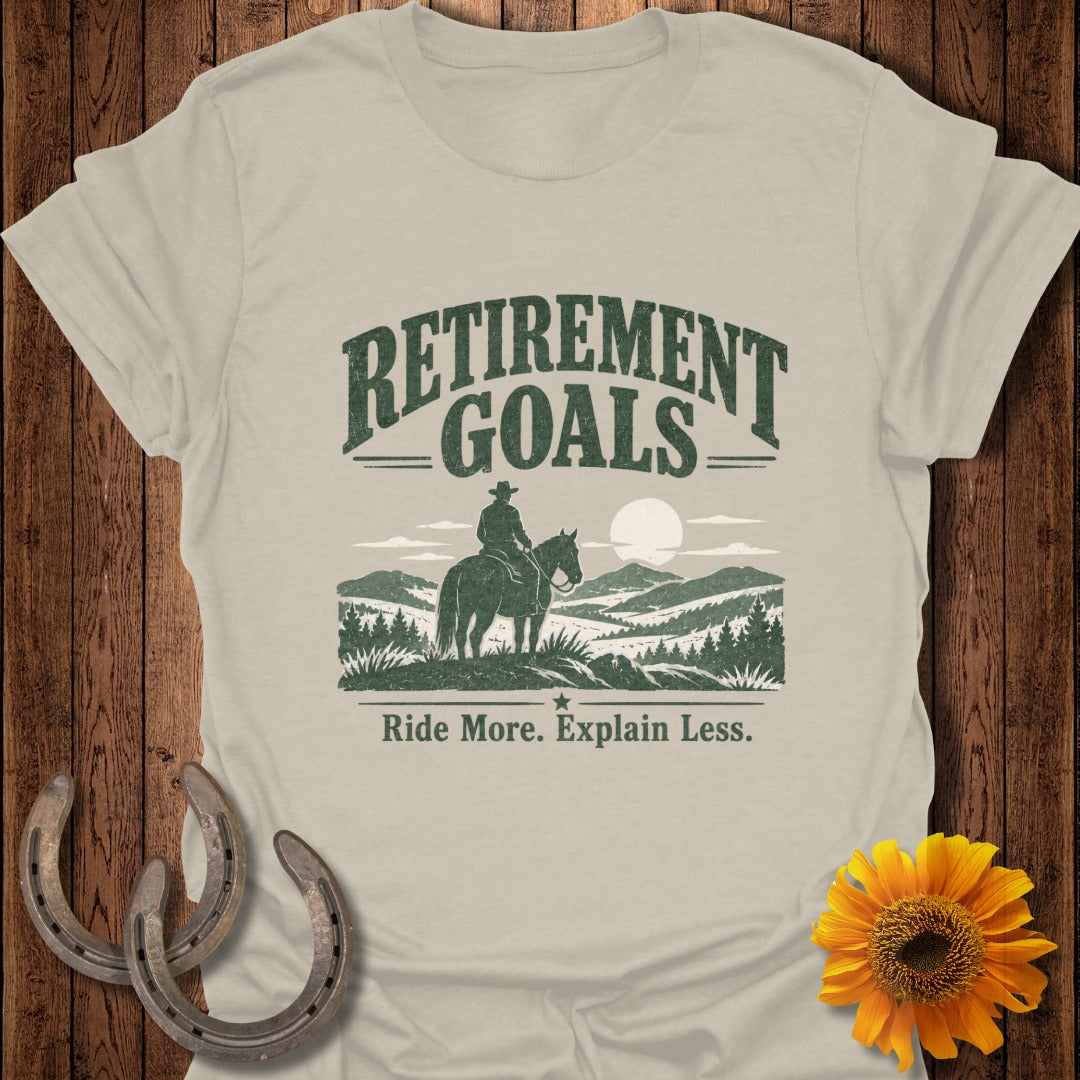 T-shirt with "Retirement Goals" text, cowboy on horse, mountains, and "Ride More. Explain Less."