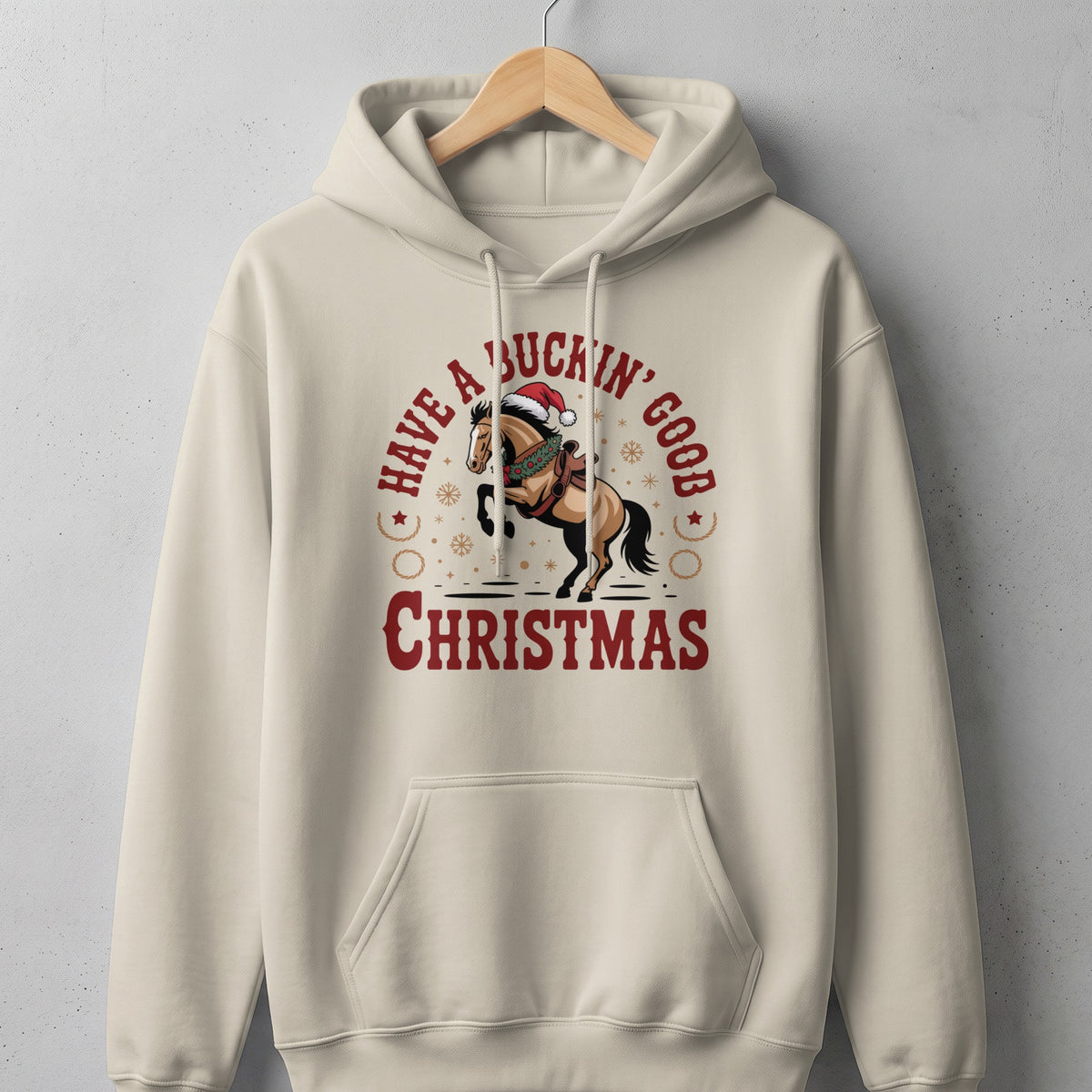 Cream hoodie with a bucking horse wearing a Santa hat and the text "Have a Buckin' Good Christmas".