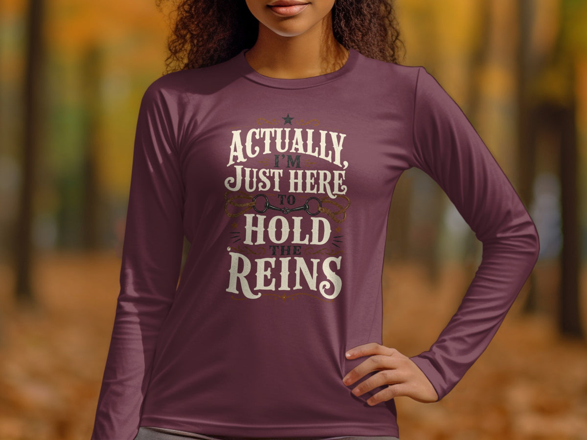 Long-sleeved shirt with text "Actually, I'm Just Here To Hold The Reins" and horse bit graphic.