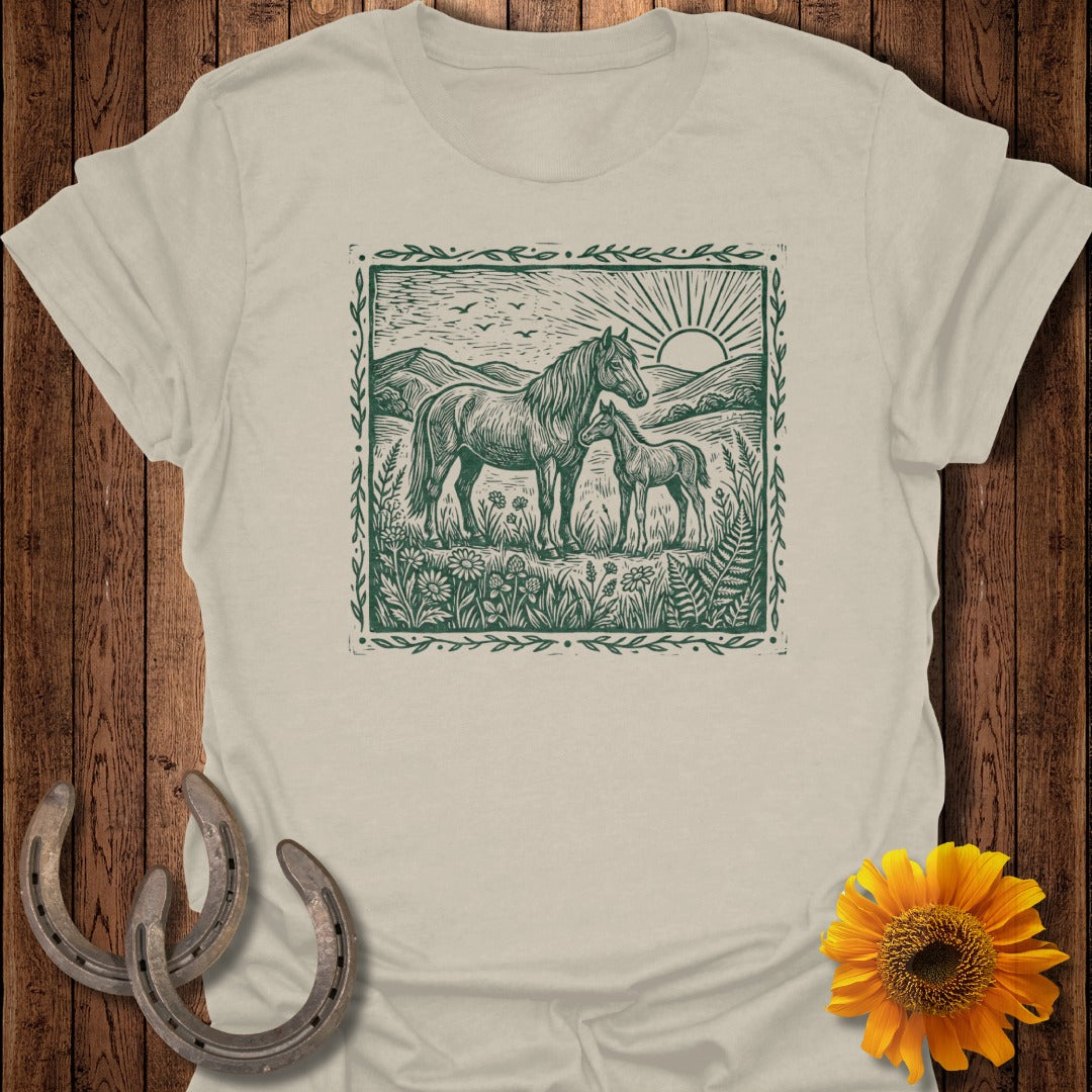 Horse and foal in a field with sun, mountains, and floral border.