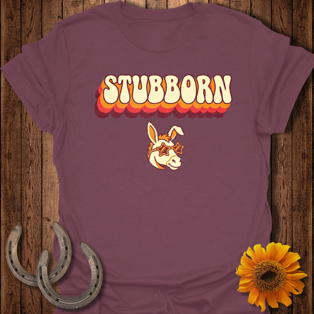 Burgundy t-shirt with retro "STUBBORN" text and cartoon donkey wearing star sunglasses.