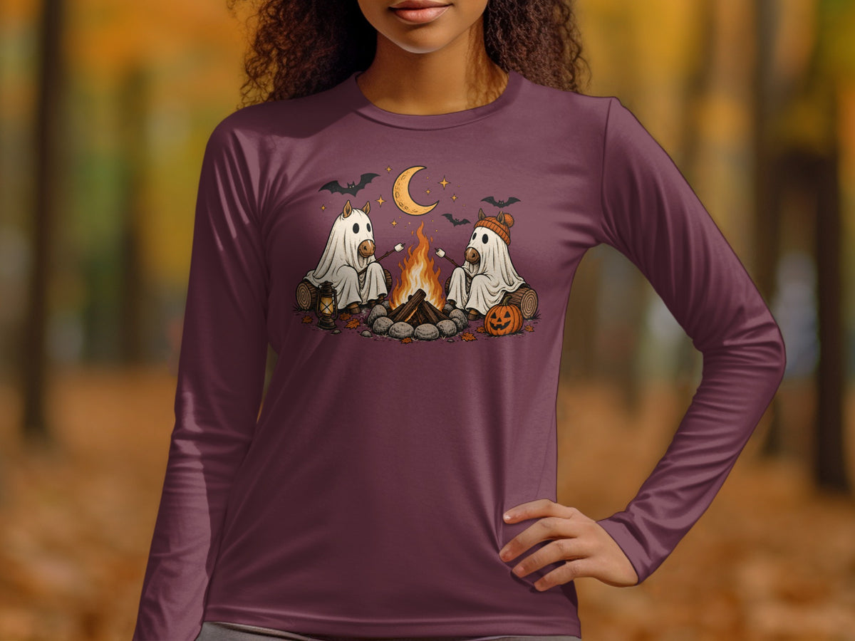 Two horses in ghost costumes roast marshmallows by a campfire under a crescent moon.