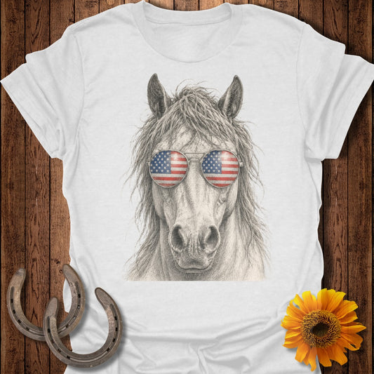 Horse wearing American flag sunglasses on white t-shirt with rustic wood and horseshoe background.