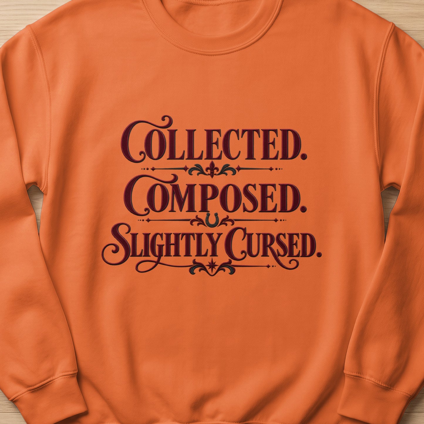 Orange sweatshirt with "Collected. Composed. Slightly Cursed." text.