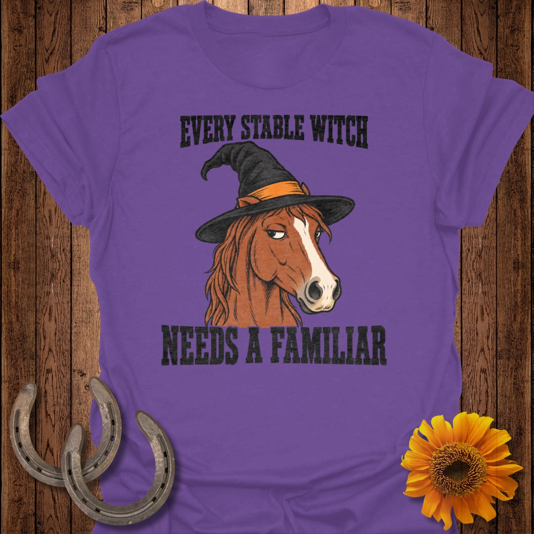 Purple t-shirt with a horse wearing a witch hat and text that reads "EVERY STABLE WITCH NEEDS A FAMILIAR".