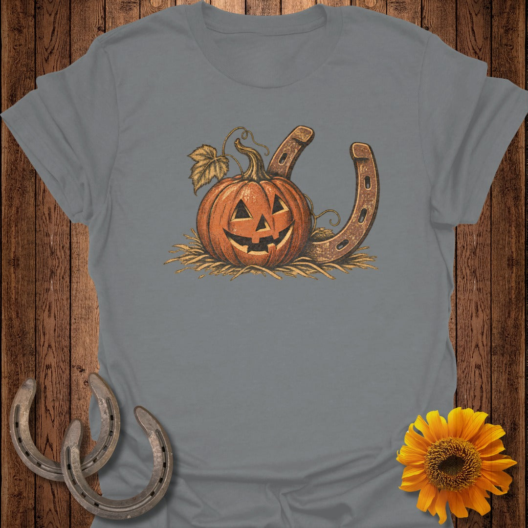 Jack-o'-lantern pumpkin with horseshoes on a straw-covered t-shirt graphic.