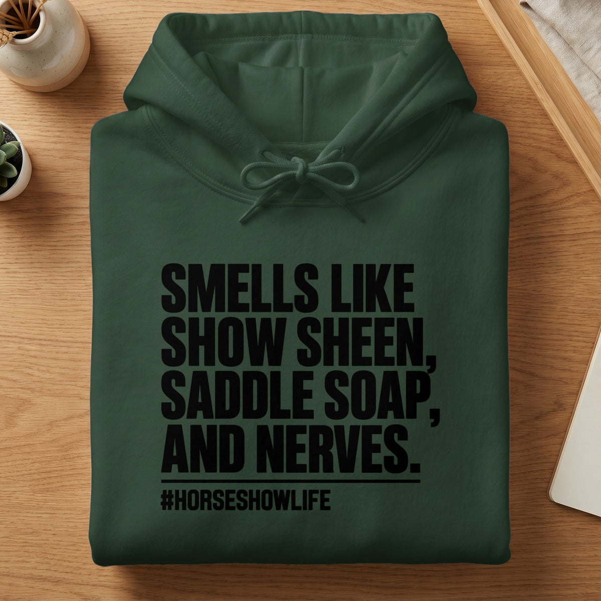 Dark green hoodie with text "Smells Like Show Sheen, Saddle Soap, and Nerves. #HorseShowLife".