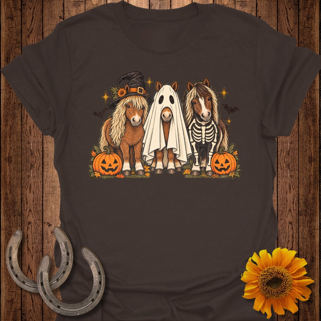 Three horses dressed for Halloween: one in a witch hat, one as a ghost, one as a skeleton.