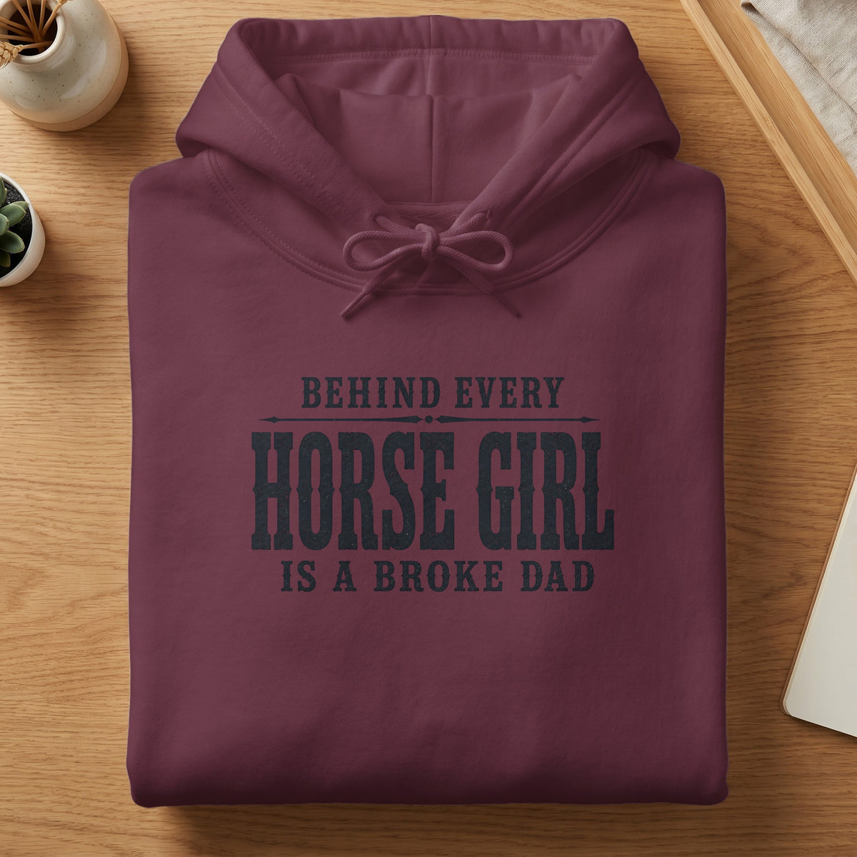 Maroon hoodie with "Behind Every Horse Girl Is A Broke Dad" text.
