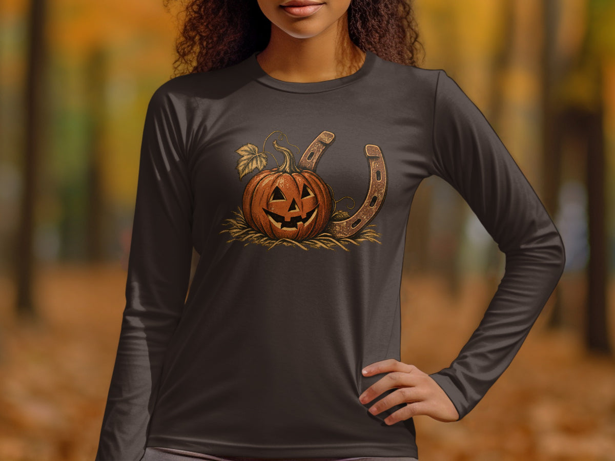 Jack-o'-lantern pumpkin with horseshoe on hay on a dark long-sleeve shirt.
