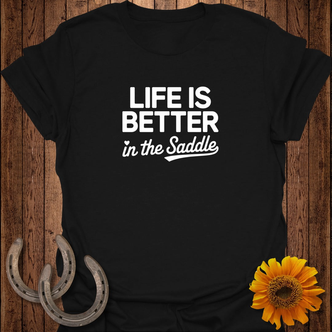 Black t-shirt with white text "LIFE IS BETTER in the Saddle" and horseshoe accents.
