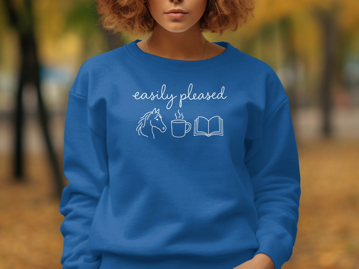 Blue sweatshirt with white text "easily pleased" and horse, coffee, book icons.