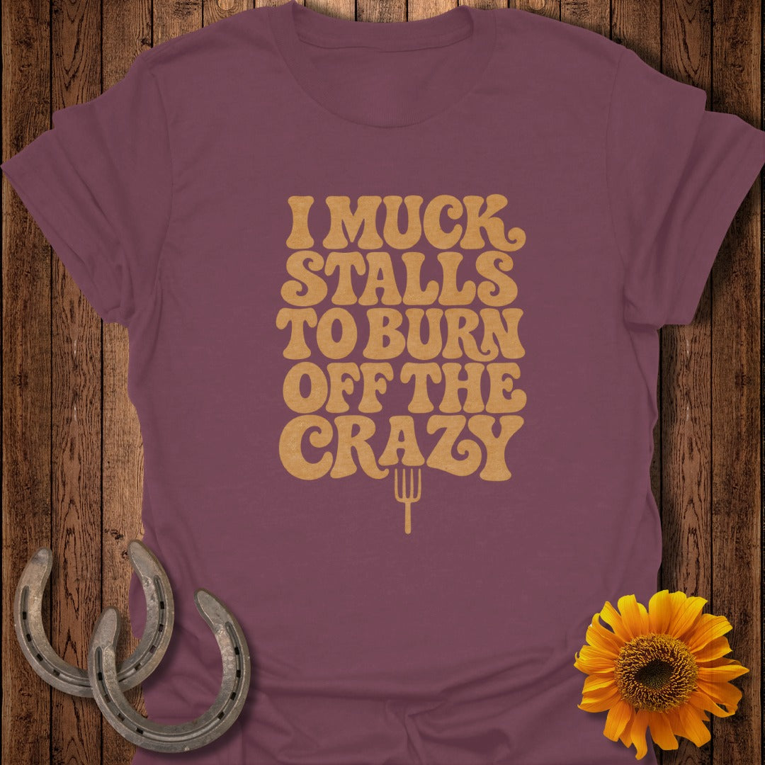 A plum t-shirt featuring yellow vintage lettering that reads I MUCK STALLS TO BURN OFF THE CRAZY.
