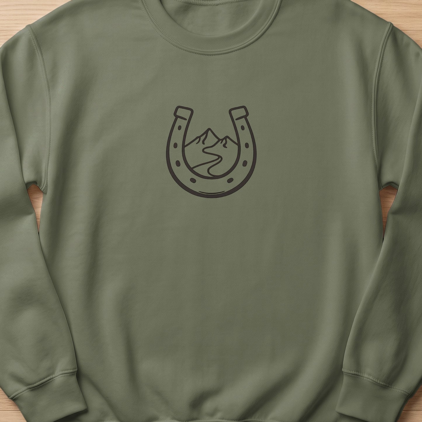 Olive green crewneck sweatshirt with a dark gray horseshoe and mountain outline graphic.