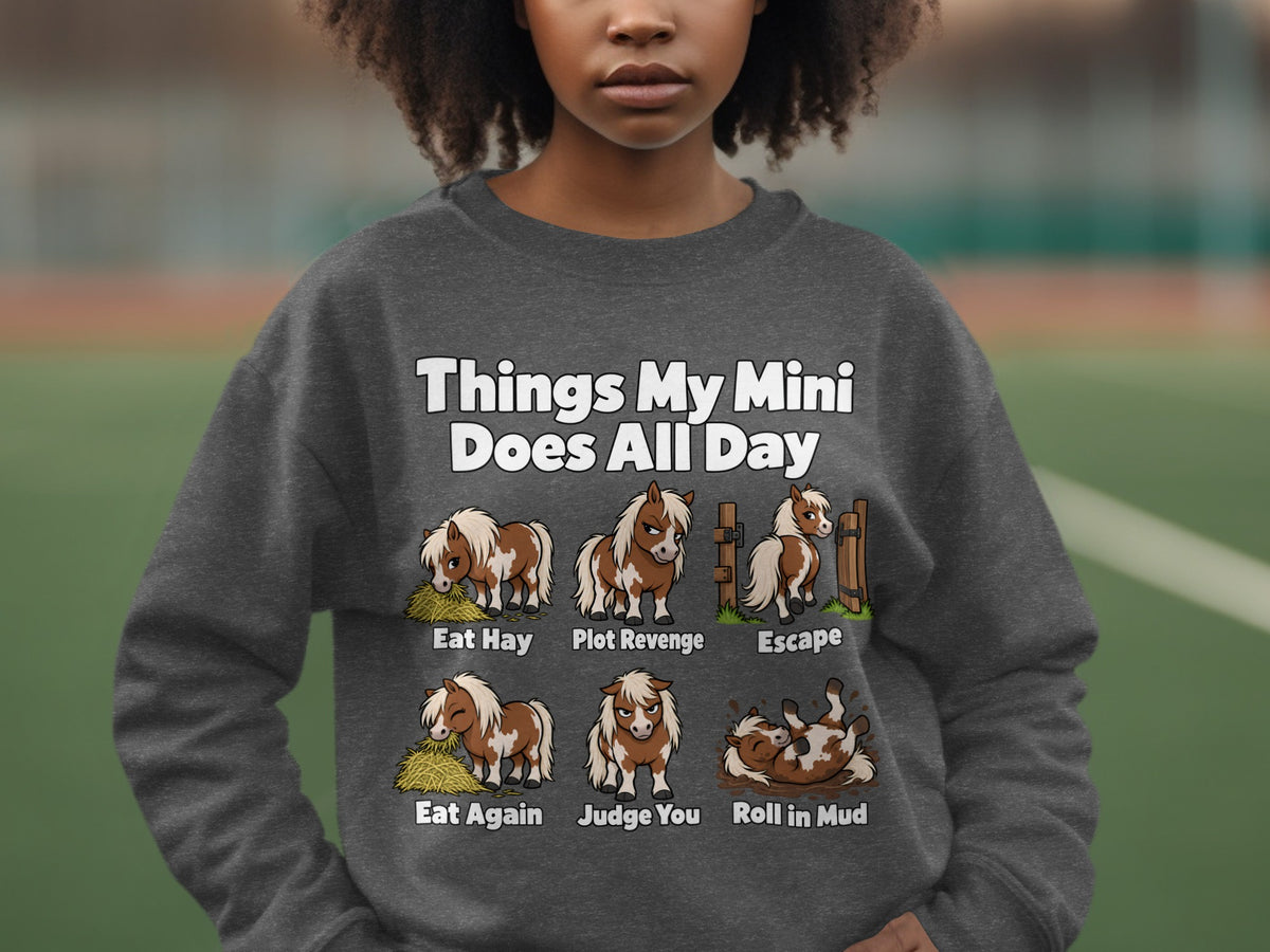 A person wearing a gray crewneck sweatshirt printed with six illustrations of a miniature horse and humorous captions.