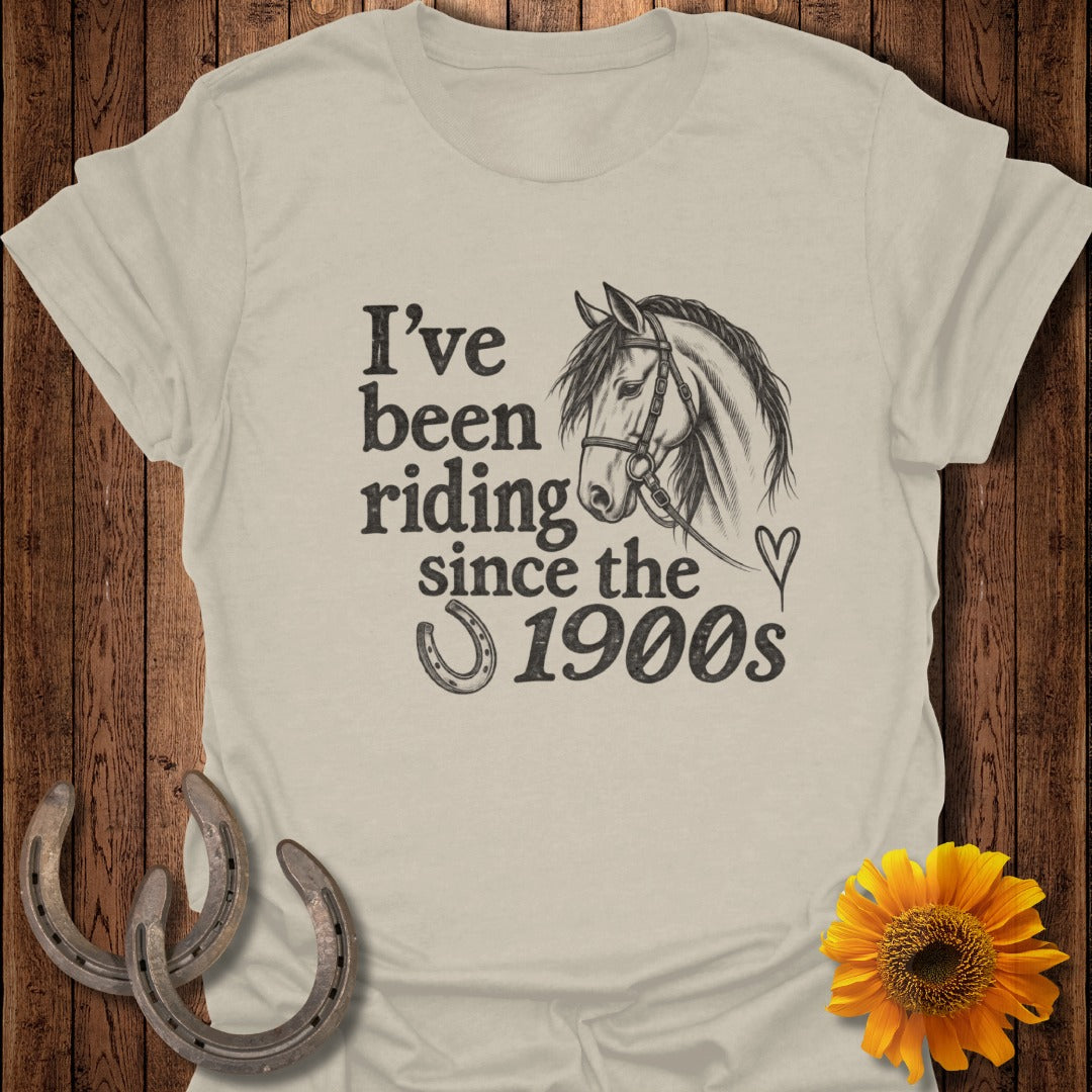 Light tan t-shirt with graphic "I've been riding since the 1900s" and horse illustration.