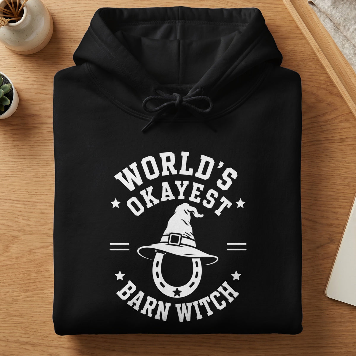 Black hoodie with white text "World's Okayest Barn Witch" and witch hat.
