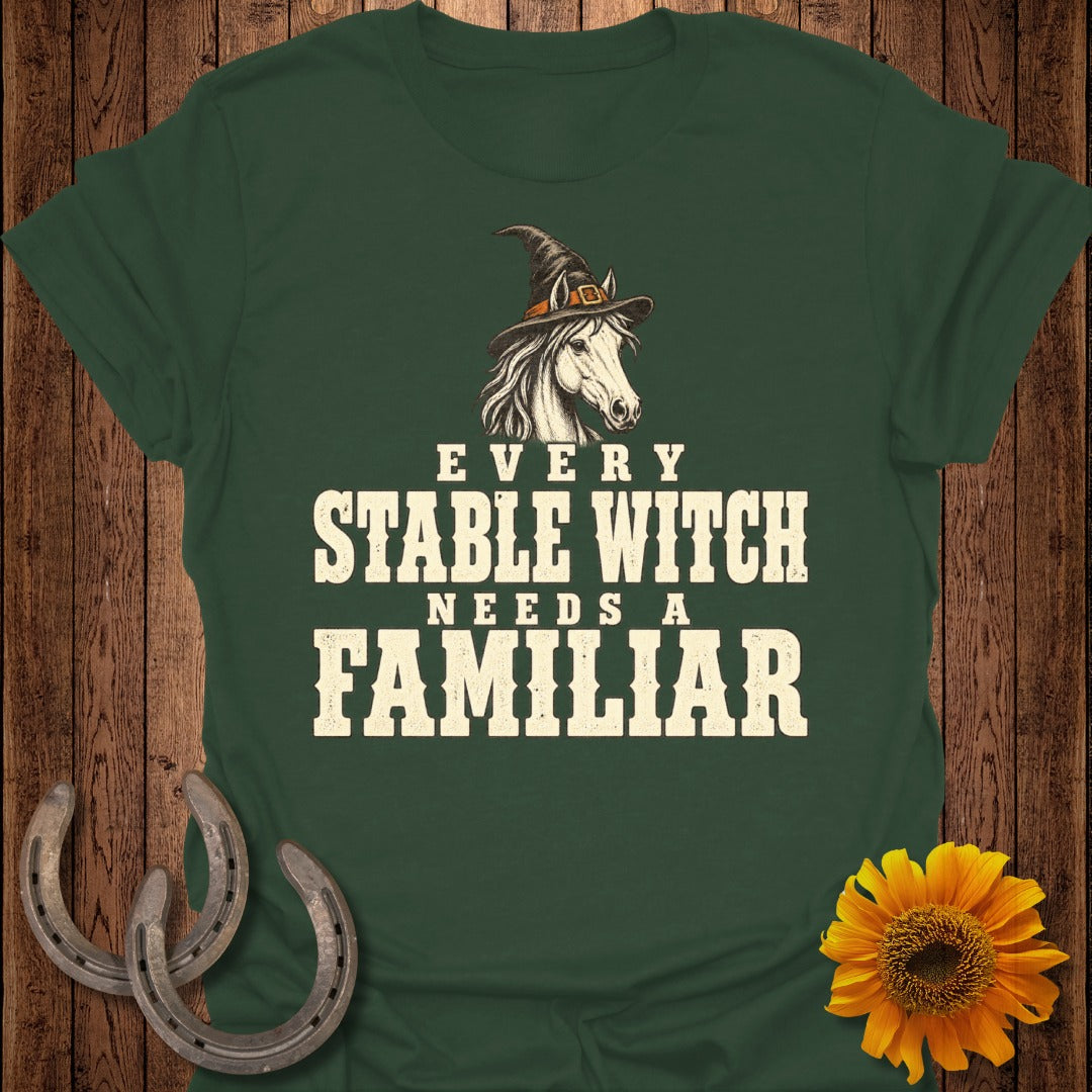Dark green t-shirt with text "EVERY STABLE WITCH NEEDS A FAMILIAR" and a horse in a witch hat.