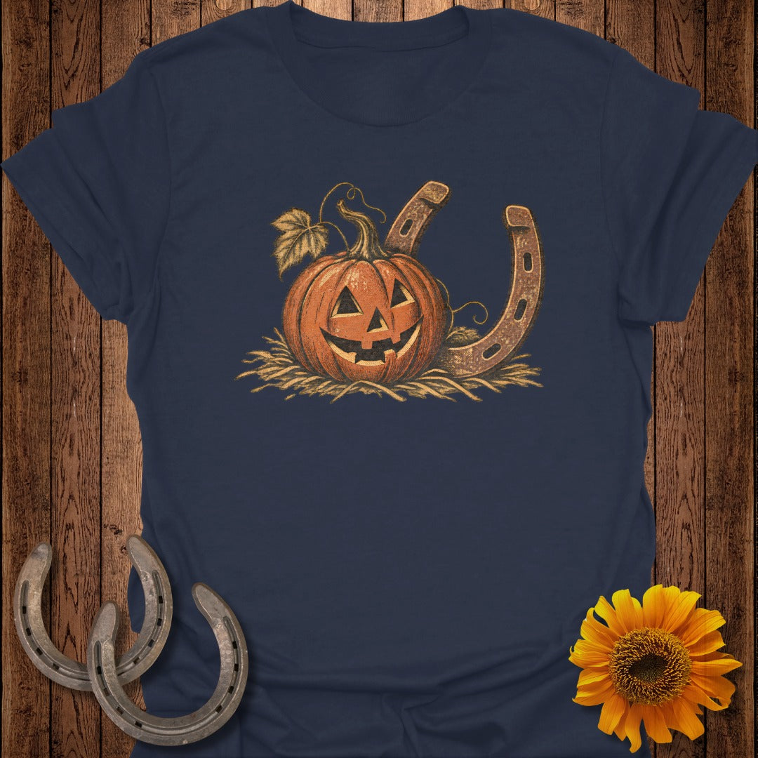 Navy t-shirt with a carved jack-o'-lantern and horseshoe graphic on straw.