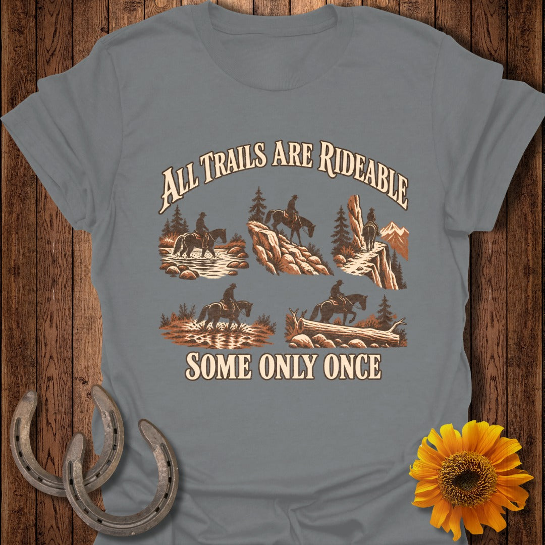 T-shirt with illustration of cowboys on horseback navigating various terrains and text "All Trails Are Rideable Some Only Once".