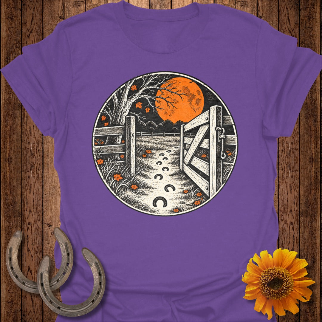 Purple t-shirt with a circular design of a fence, open gate, and horseshoe prints under an orange moon.