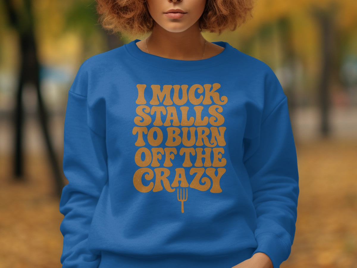 Blue sweatshirt with orange text "I muck stalls to burn off the crazy" and a fork.