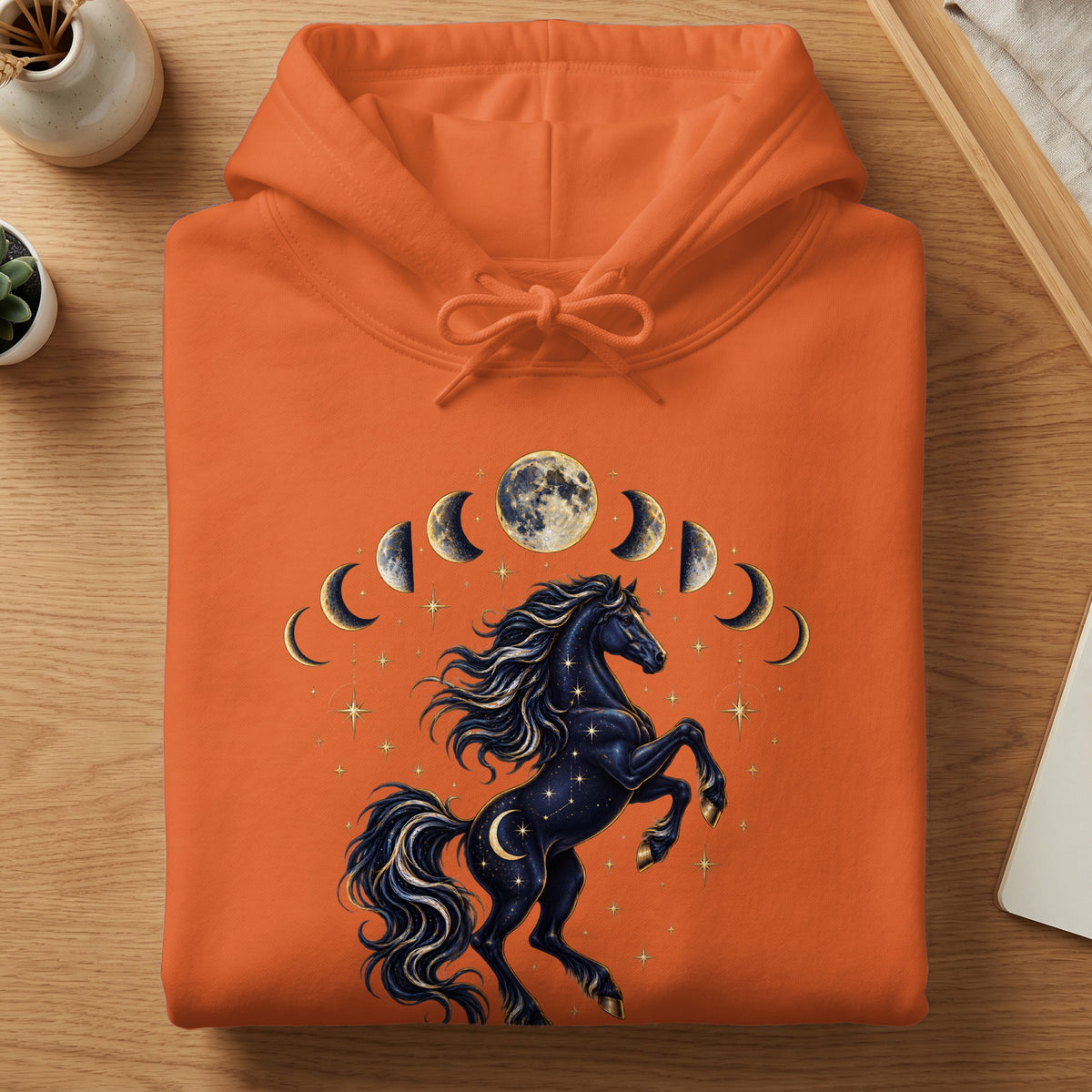 Orange hoodie with a celestial black horse and moon phases graphic.