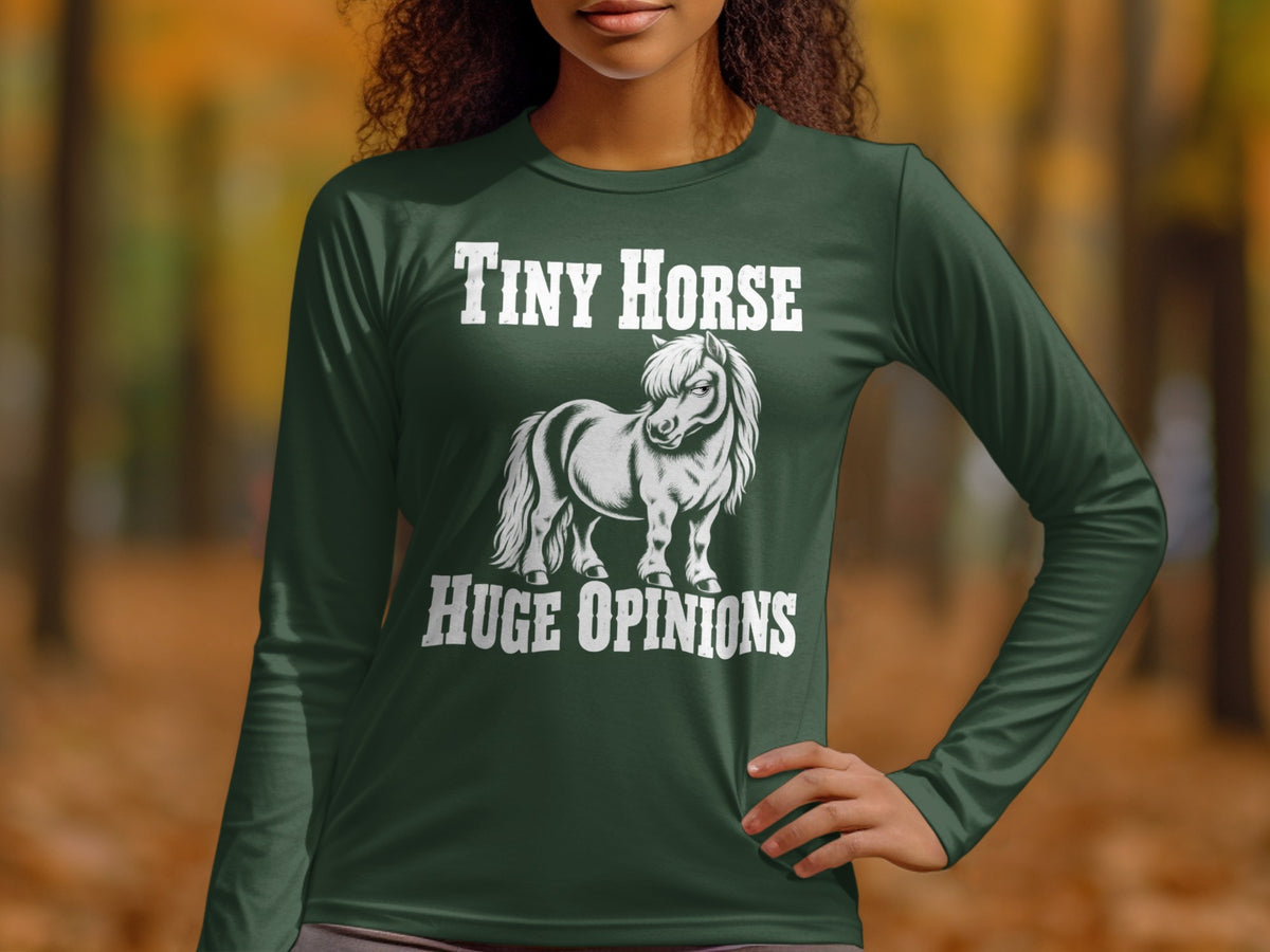 A person wearing a dark green long-sleeved t-shirt with white text reading Tiny Horse Huge Opinions and an illustration of a pony.