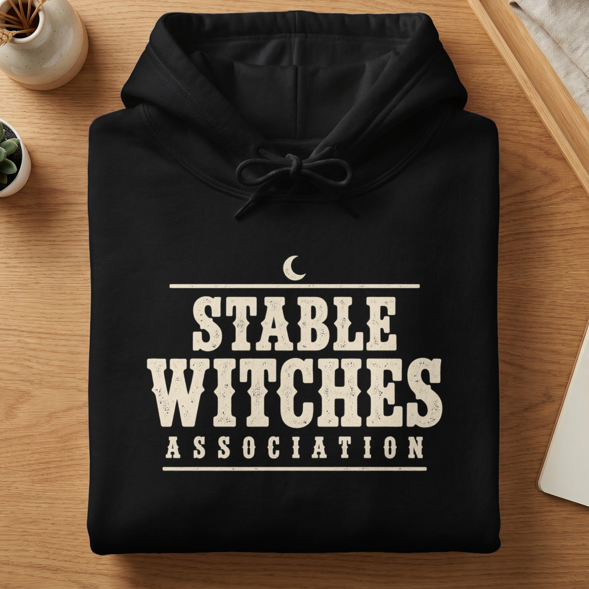 Black hoodie with "STABLE WITCHES ASSOCIATION" text and a crescent moon graphic.