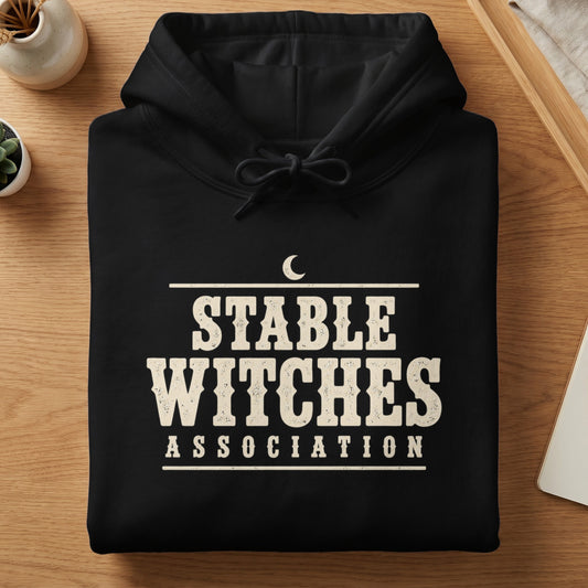 Black hoodie with "STABLE WITCHES ASSOCIATION" text and a crescent moon graphic.