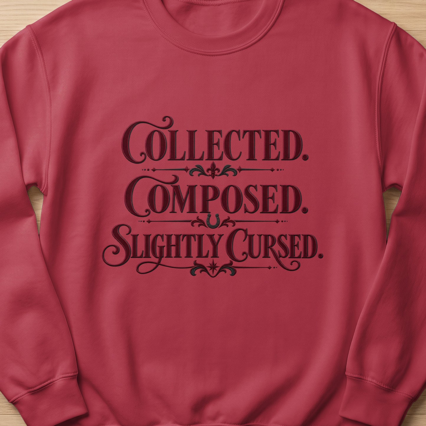 Maroon sweatshirt with text: Collected. Composed. Slightly Cursed.