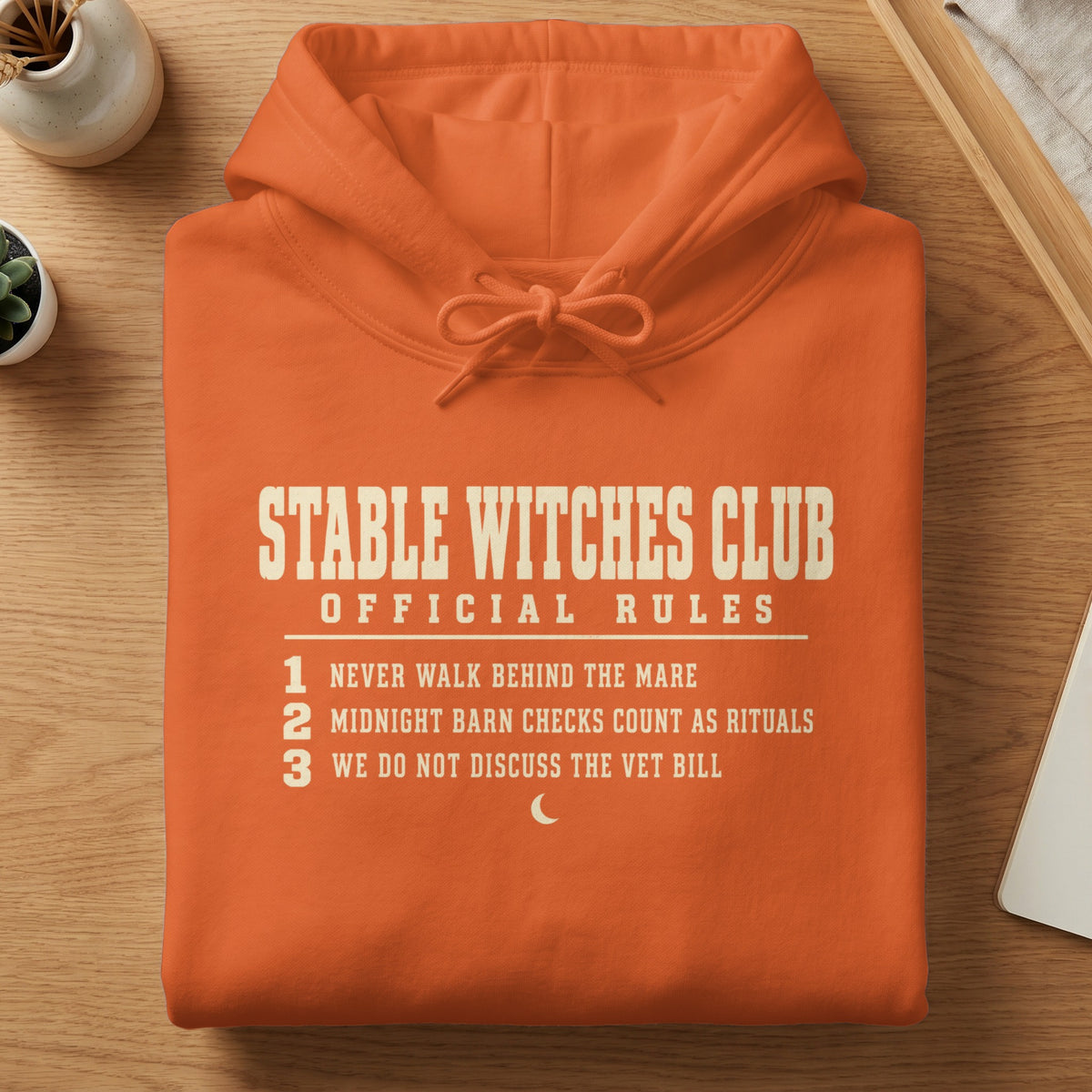 Orange hoodie with "Stable Witches Club Official Rules" text and moon graphic.