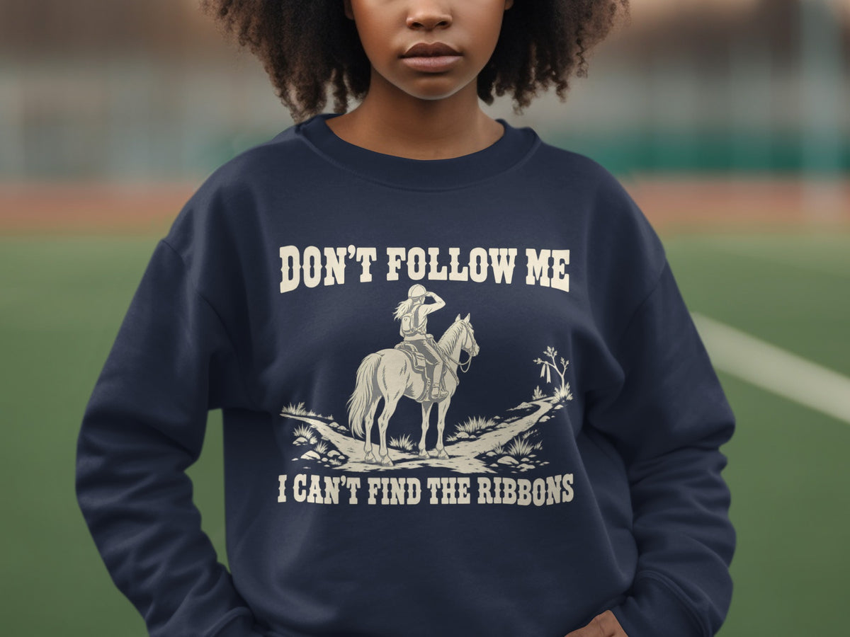 A dark blue crewneck sweatshirt featuring a white graphic of a horse and rider with the text DON'T FOLLOW ME I CAN'T FIND THE RIBBONS.