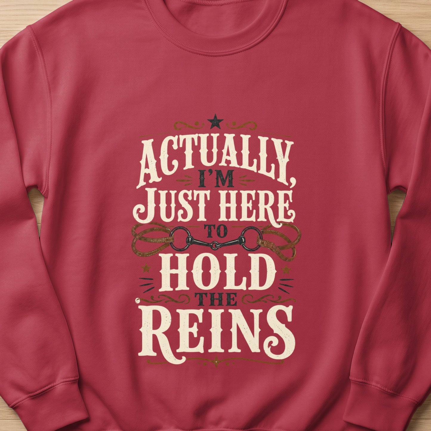 Red sweatshirt with "Actually, I'm Just Here To Hold The Reins" text and horse bit graphic.