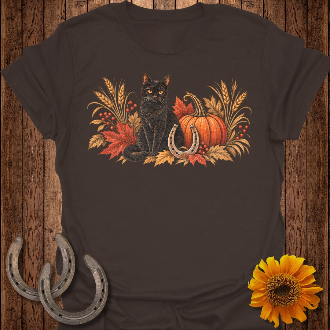 Black cat with pumpkin, horseshoe, and fall foliage graphic on a brown t-shirt.