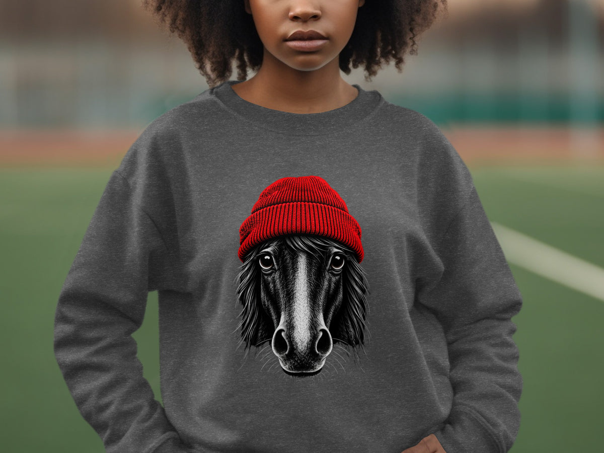 A person wearing a gray crewneck sweatshirt featuring a graphic of a horse wearing a red beanie.