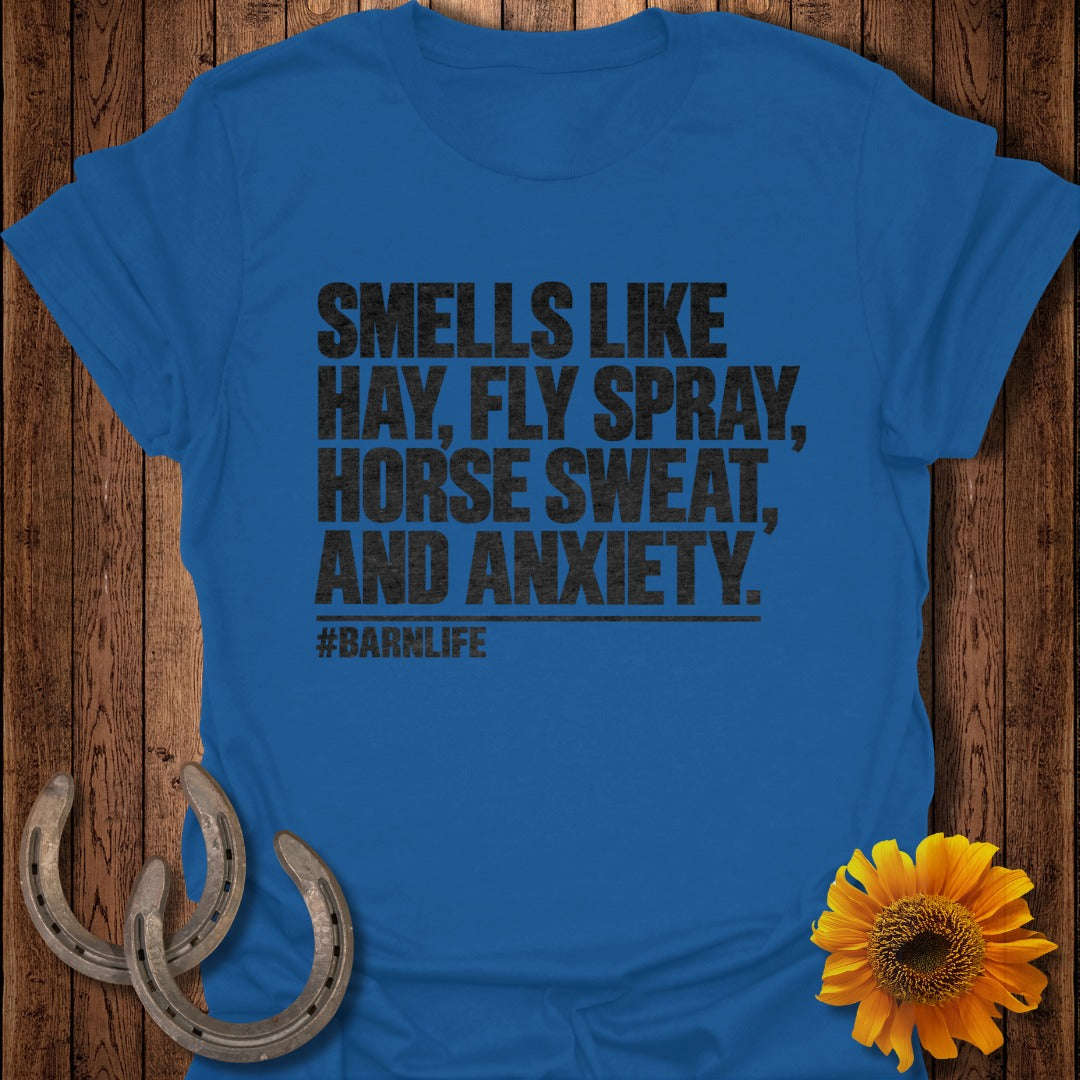 Blue t-shirt featuring black text that reads SMELLS LIKE HAY, FLY SPRAY, HORSE SWEAT, AND ANXIETY. #BARNLIFE.