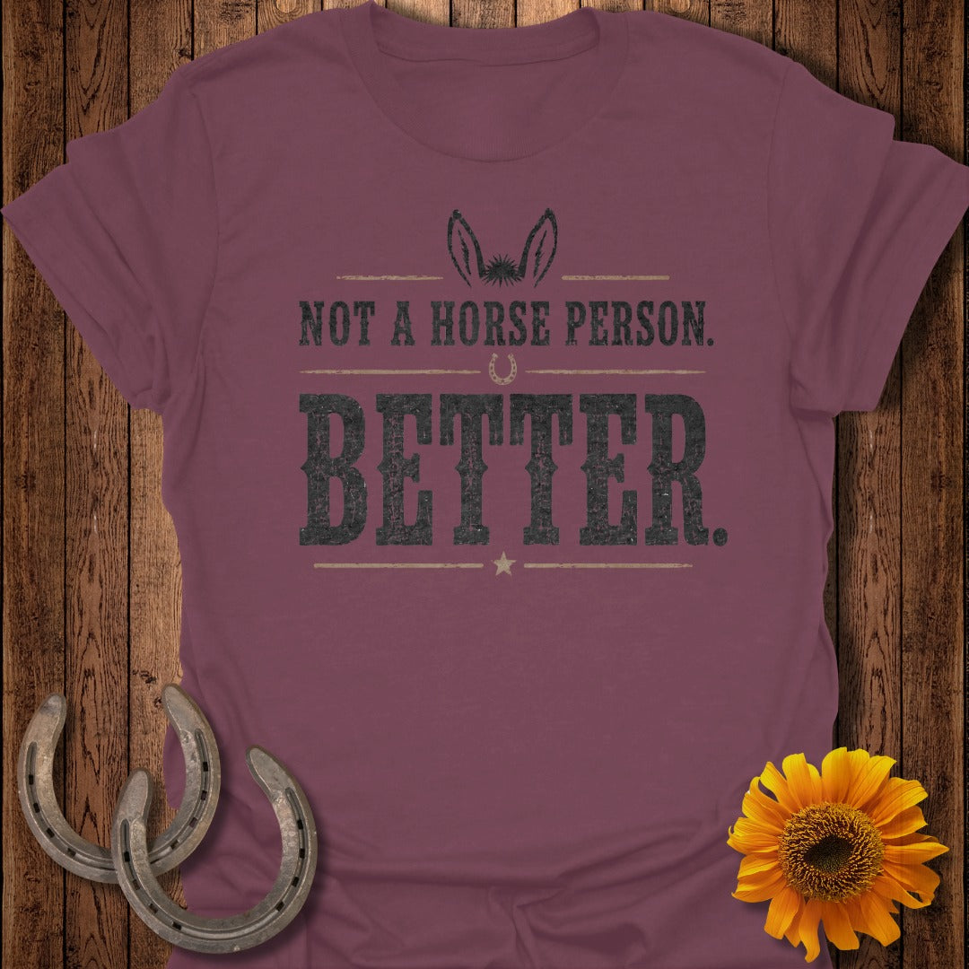 Maroon t-shirt with text "NOT A HORSE PERSON. BETTER." and donkey ears graphic.