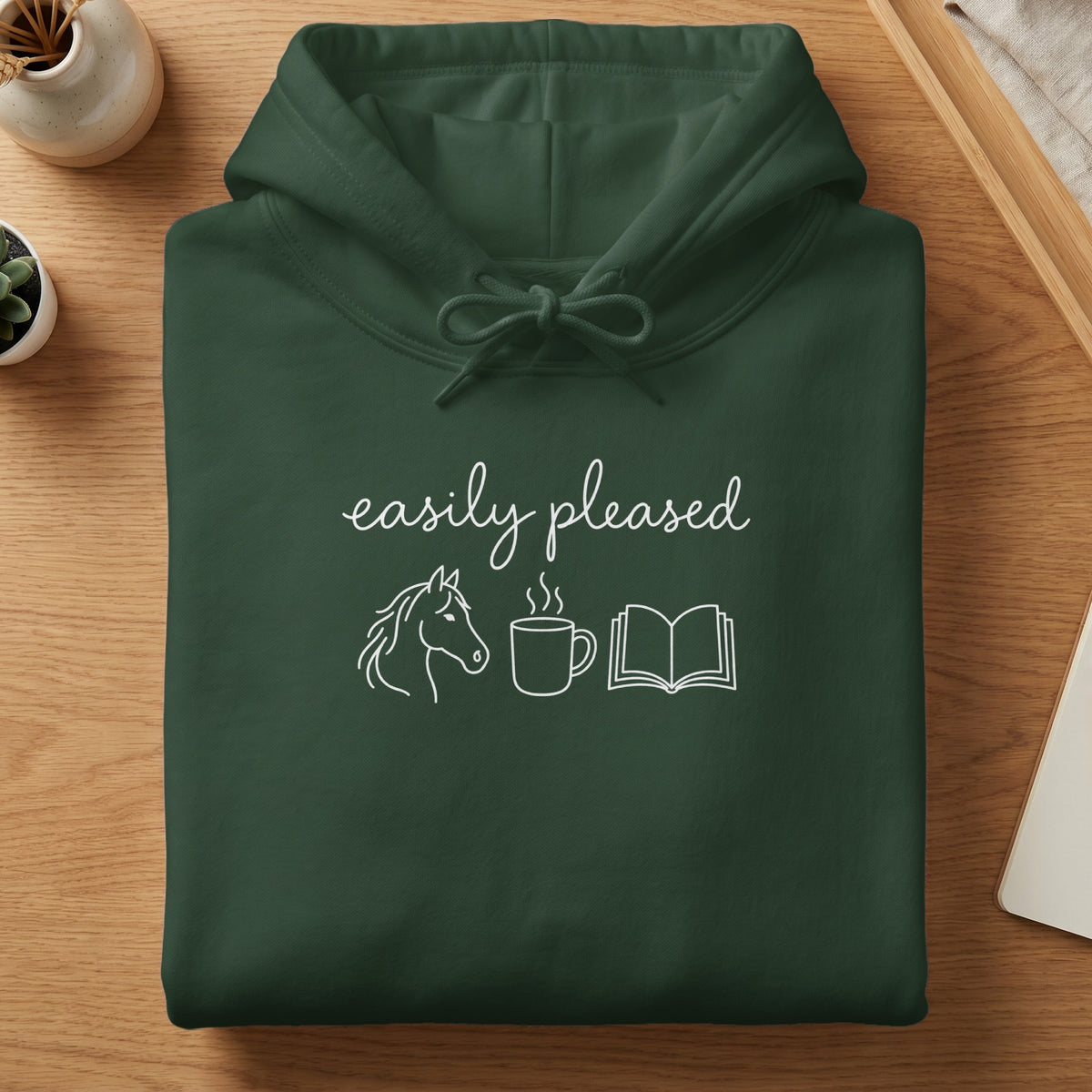 Dark green hoodie with "easily pleased" text and horse, coffee, and book icons.