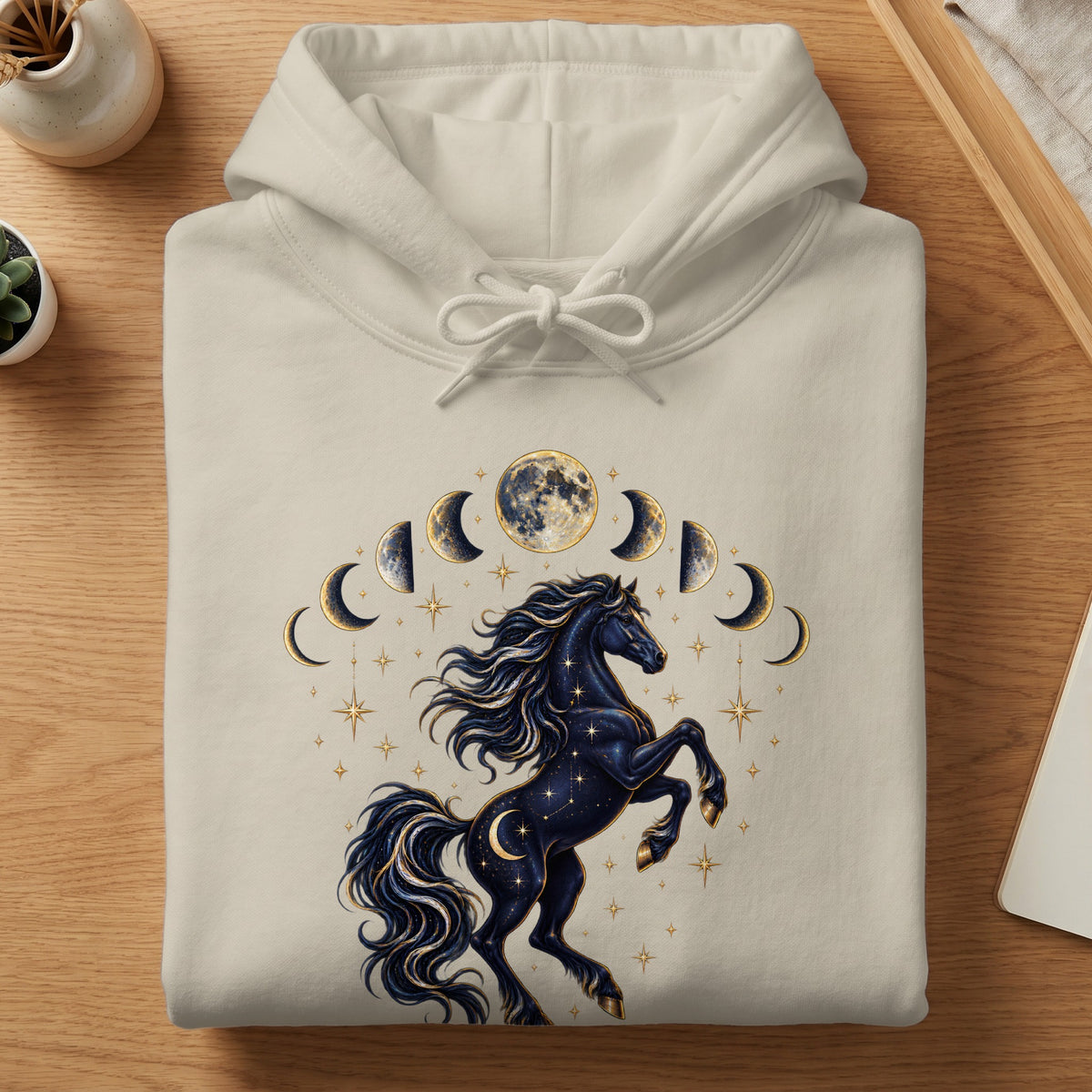 Cream hoodie featuring a dark starry horse with moon phases and stars graphic.